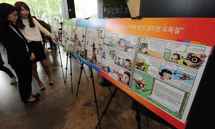 시민들이 저작권 침해에 대한 내용를 그린 만화를 보고 있습니다.