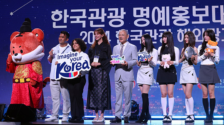 외국인 참여자들과 함께 홍보판넬 imagine your Korea, 캐릭터 인형을 들고 있는 뉴진스와 유인촌 장관 