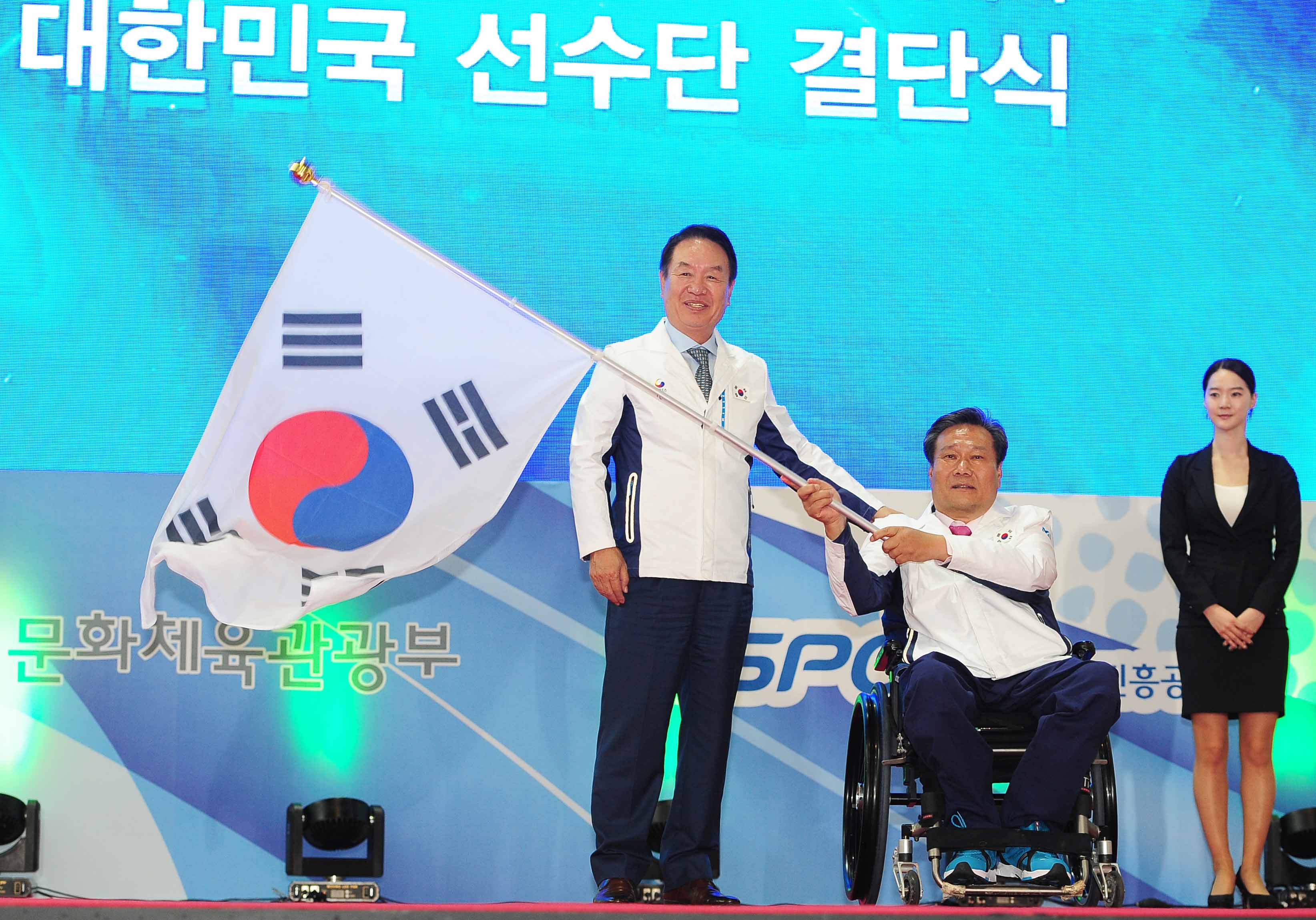 김성일 대한장애인체육회 회장이 김락환 선수단장에게 단기를 전달하고 있다.