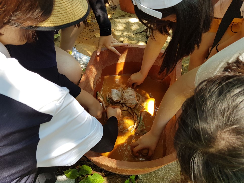 야외로 이동해서 미리 준비된 황토물에 손수건을 염색하고 있는 학생들