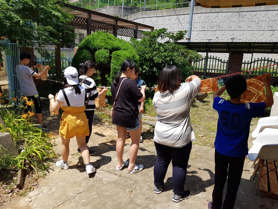 자신이 염색한 손수건을 정성스레 빨랫줄에 매달고 있는 학생들